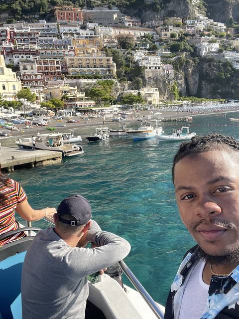 Two people on a boat with a coastal town view.