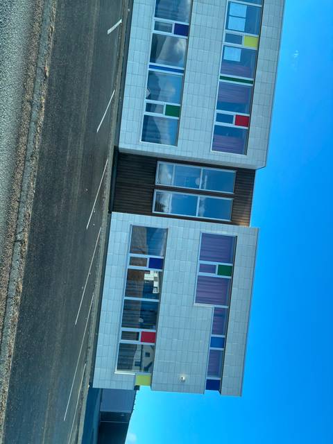       Modern building with colorful windows and a clear blue sky.
  