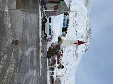       A church with a red roof, snowy landscape, and road.
  