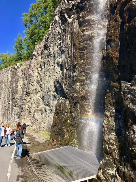 People enjoying a waterfall with a rainbow effect.