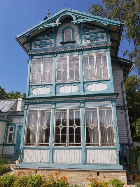       A wooden house with decorative white and blue panels.
  