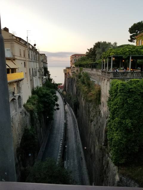       Upside-down view of an urban road and buildings leading to the sea.
  