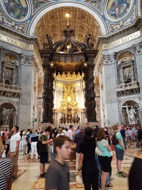       Upside-down interior of a church with ornate designs and many visitors.
  