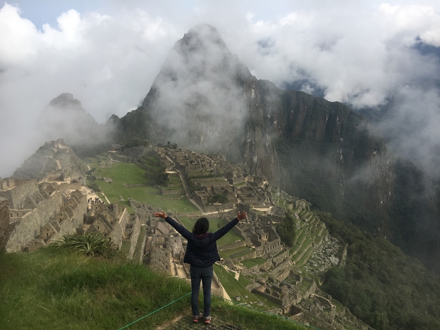 Person with arms raised overlooking Machu Picchu.