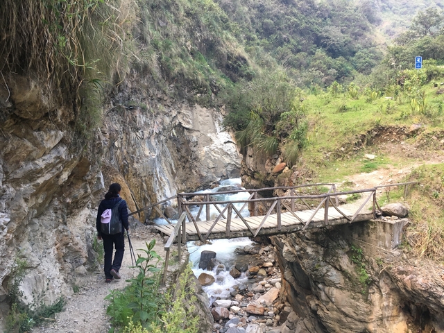 A person walking across a wooden bridge with a scenic view.