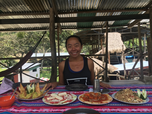 A woman sitting at a table with local foods.