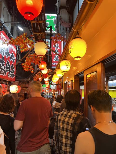       People walking through lit alley with lanterns.
  
