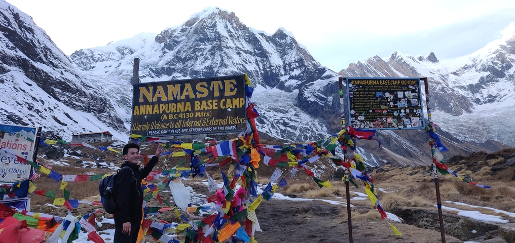 Annapurna Base Camp sign with mountainous backdrop.