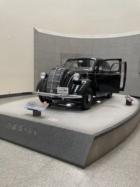       Classic car display with museum visitors observing.
  