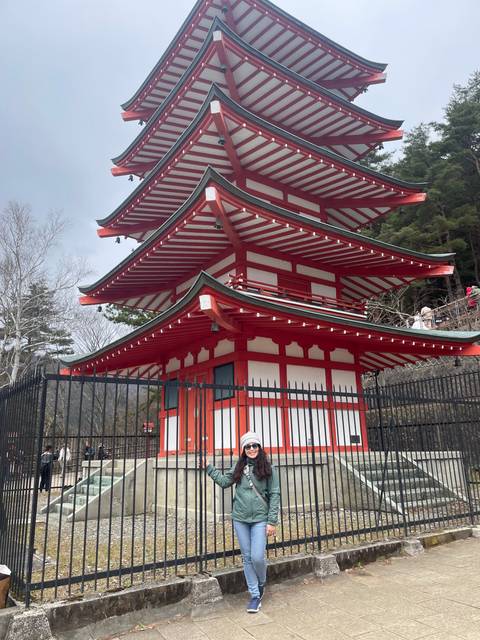       Woman posing beside a multi-tiered pagoda.
  