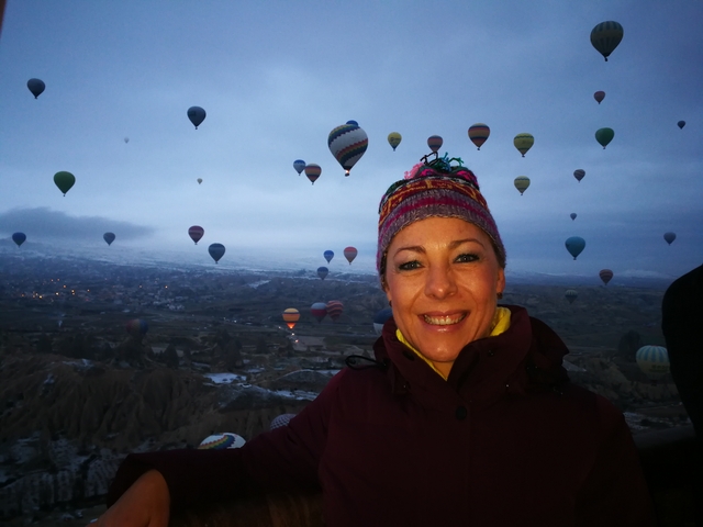 Person with background of hot air balloons over a scenic valley.