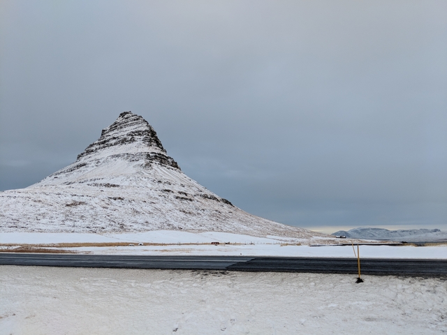       Snow-covered mountain with a clear sky, likely Kirkjufell in Iceland.
  