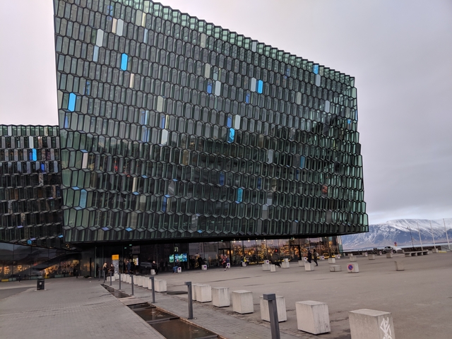       Modern glass building with a mountain backdrop.
  