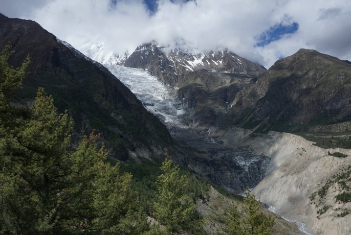 Mountain valley with a glacier and snow-capped peaks.
