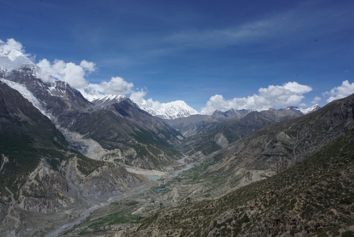 Expansive view of mountains and valley with cloudy sky.