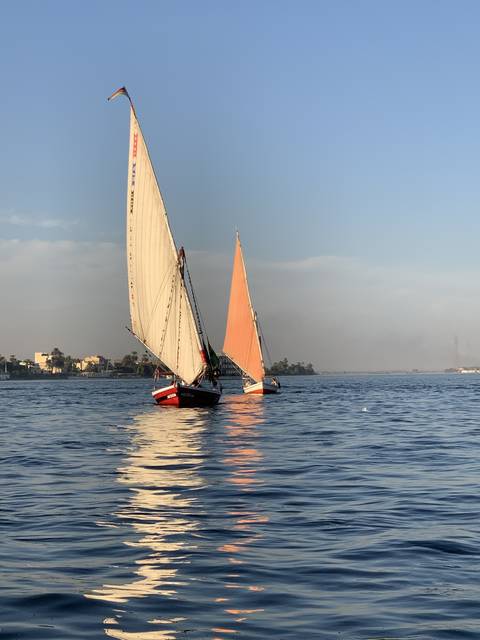 Sailboats on a large body of water during sunset.