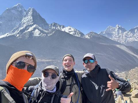 Group of hikers posing with a mountainous backdrop.