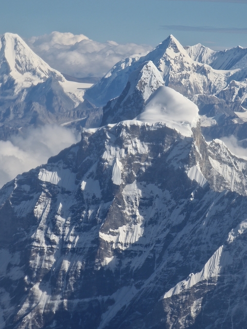 Close-up view of snowy mountain peak with surrounding clouds.