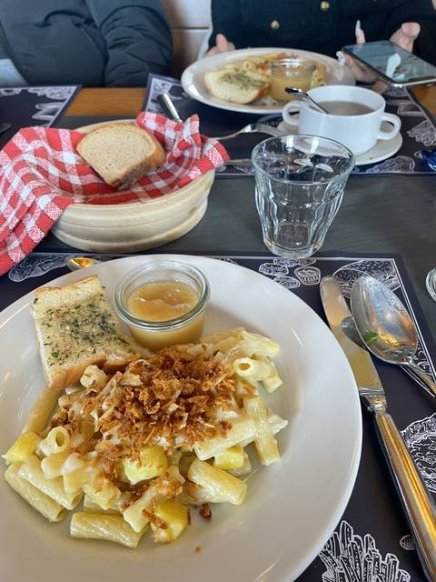 Pasta dish with toppings, bread, and garnishments.