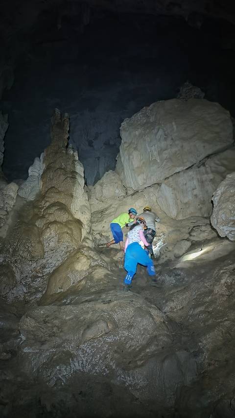 People exploring a cave with stalactites and stalagmites.