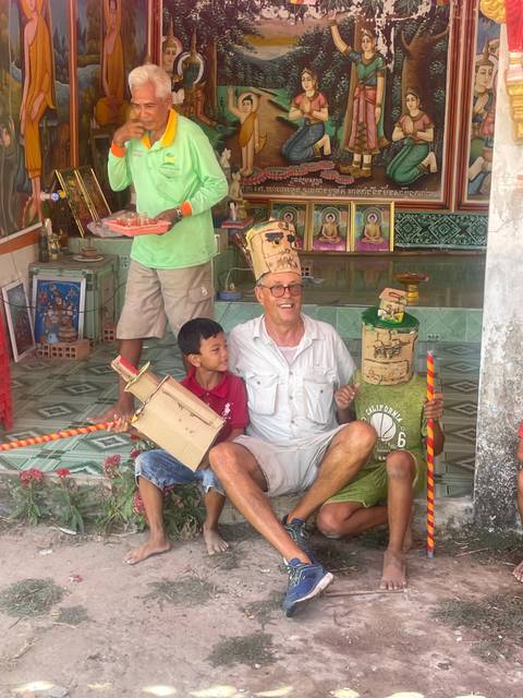 Two men and a child pose in front of a wall with intricate art.