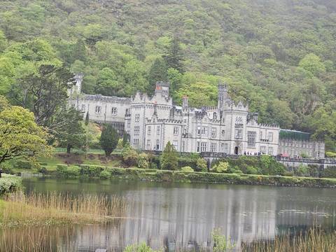 Kylemore Abbey reflected in the water with lush greenery around.