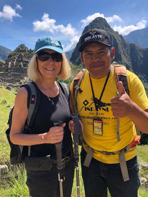       Two hikers posing with trekking poles against a mountainous backdrop.
  