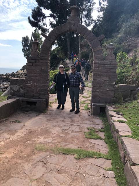       Elderly couple walking through an arched stone gate.
  
