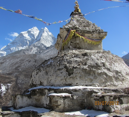       Stupa with prayer flags in front of snow-capped mountains.
  
