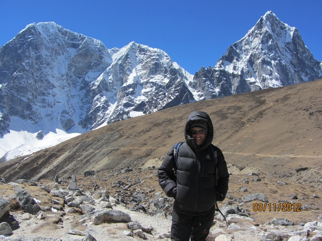       Person in outdoor gear posing in a mountainous area.
  