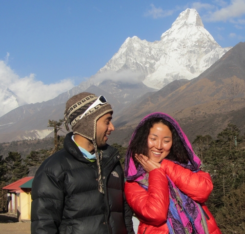       Two smiling people with mountains in the background.
  