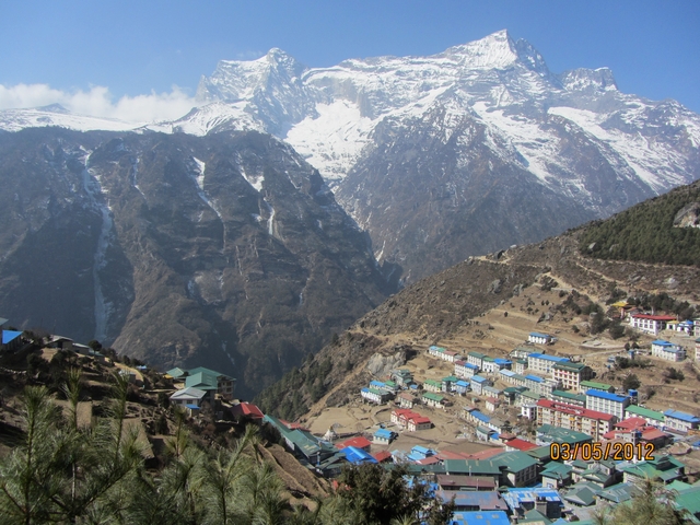       Mountain village with colorful houses and snowy peaks.
  