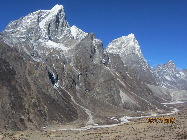       Rocky, snowy peaks under a bright blue sky.
  