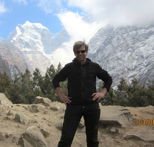       A person posing with snow-capped mountains in the background.
  