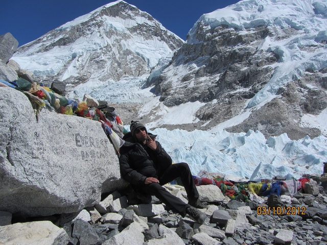       Person sitting at the Everest Base Camp with prayer flags.
  