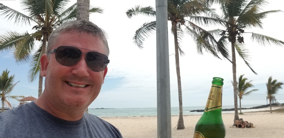 Person taking a selfie at a beach with palm trees.