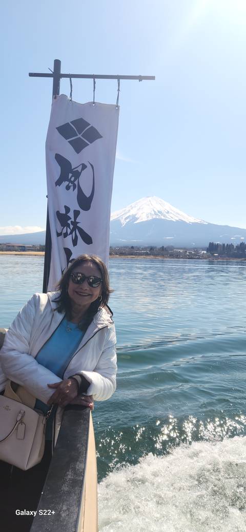 Person standing on a boat with Mount Fuji in the background.