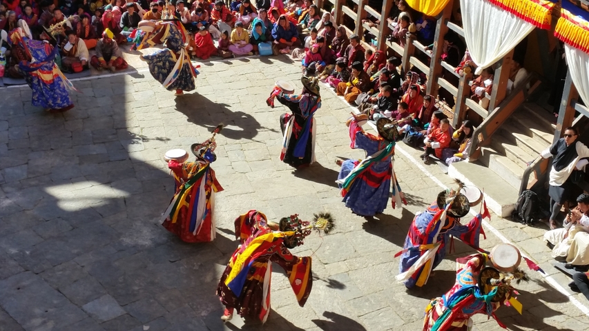       Colorful traditional dance performance in an open courtyard.
  