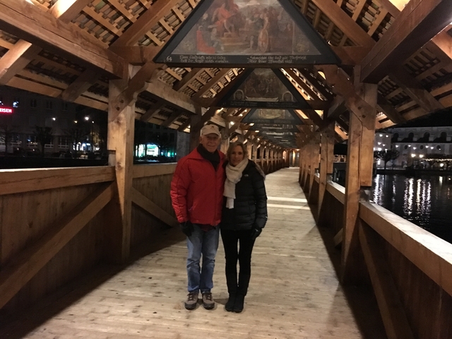       Couple posed on a wooden covered bridge at night.
  