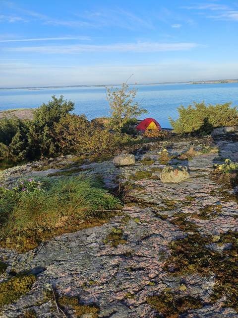       Red tent on rocky coastal terrain.
  