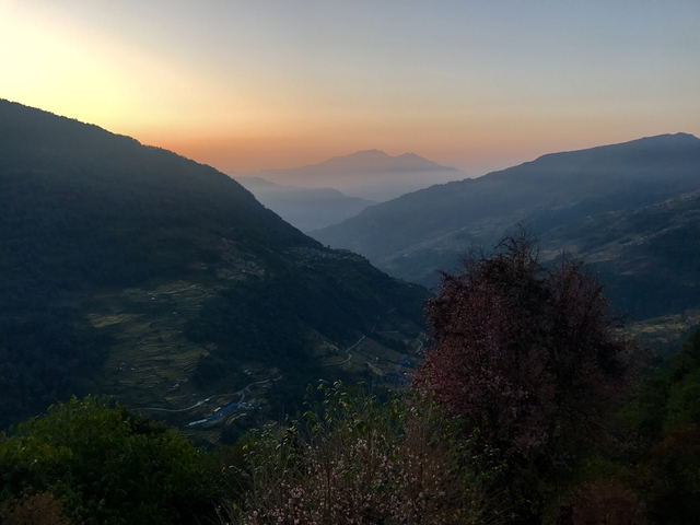 Sunset over valley with misty mountains in the background.