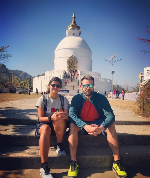       Couple sitting in front of a white monument with tourists around.
  