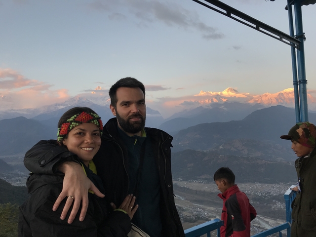       Couple embracing in front of sunset-lit mountains.
  
