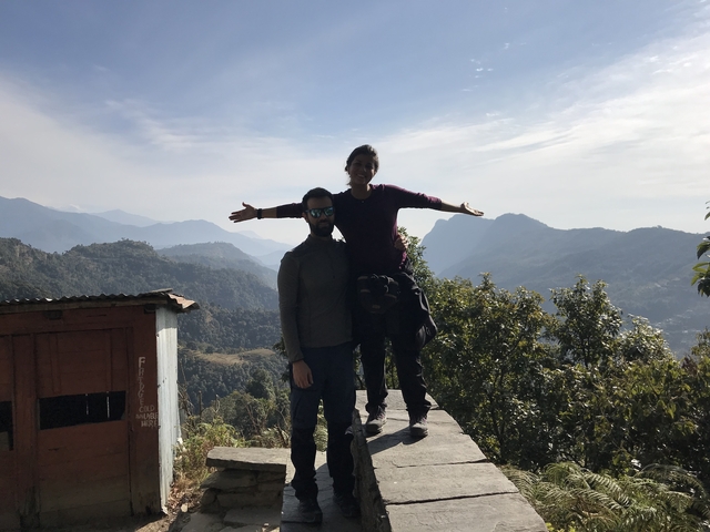       Couple posing with arms outstretched overlooking a scenic mountain view.
  