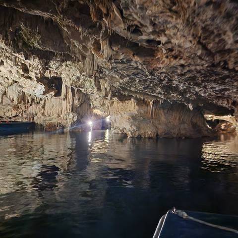       Blurry image of a cave interior with water reflections.
  