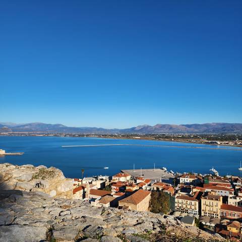 A coastal view with blue waters and red roofed buildings.