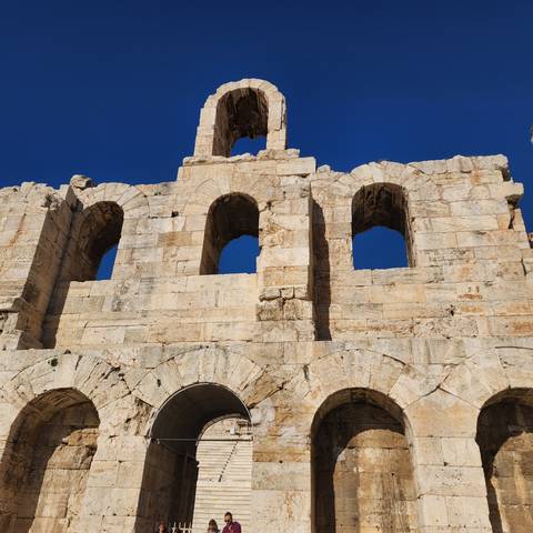       Ancient stone structure with tourists.
  