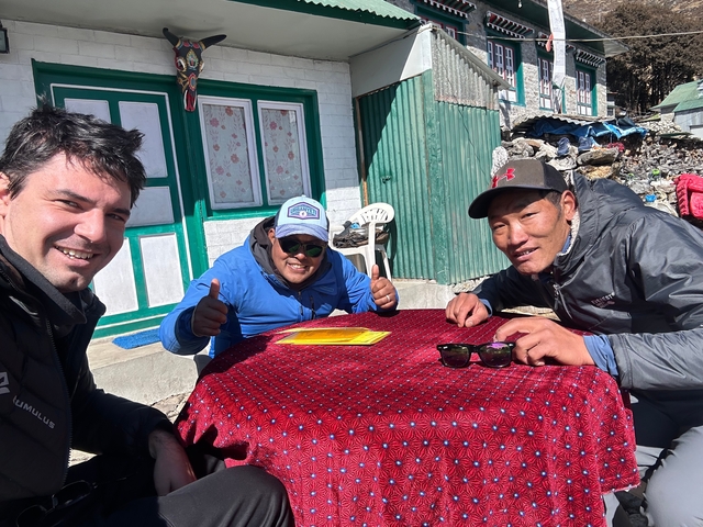 Three people sitting at a table outside a building.