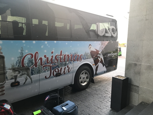 Tour bus with Christmas decorations parked outside a building.