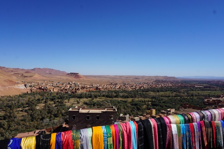 Vibrant textiles on a railing overlooking a town in a valley.